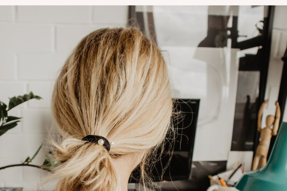 Woman at a desk with art supplies and a habit tracker to boost productivity, text reads 'Monthly Habit Tracker for Artists and Designers.'