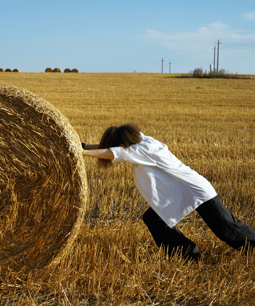 Woman pushing away a bale of straw, representing overcoming procrastination as an Artist or Designer
