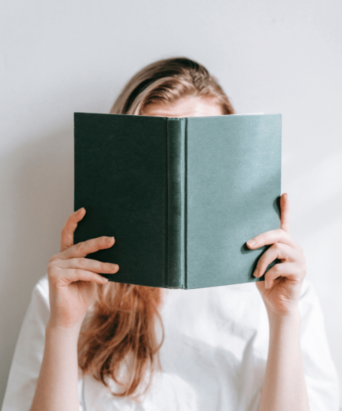 Woman reading in a book, representing learning about tips and resources for Artists and Designers.