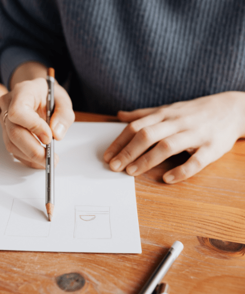 Woman sketching on a piece of paper, standing for the creative community and creative work.